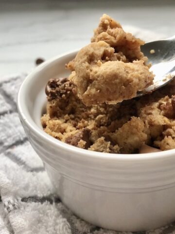 Close up of chocolate chip mug cake in ramekin dish with teaspoon