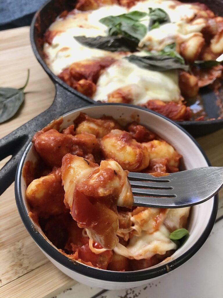 Gnocci in bowl with skillet in background